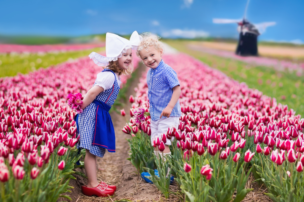 Two young kids standing in the middle of a flower field at Keukenhof 2021, dressed in typical old Dutch attire