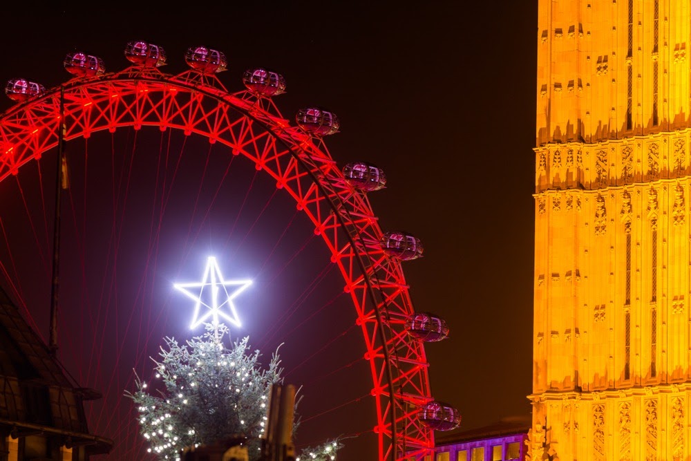The London Eye illuminated, with a Christmas tree in the background - an iconic scene of what Christmas in London looks like.