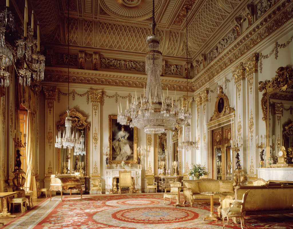 An image of the inside of Buckingham Palace, showing white and gold decorations from floor to ceiling.